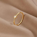 Gold ring with smooth band and small clear stone set on side view