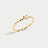 Gold ring with smooth band and small clear stone at center, angled view