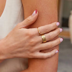 Gold ring with small clear stone on finger, paired with textured gold band