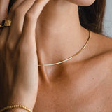 Gold snake choker necklace with smooth slim link chain across collarbone