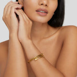 Gold coiled bracelet on wrist, stacked parallel loops with ribbed texture