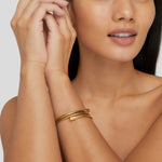 Gold coiled bracelet cuff on wrist with stacked ridged strands