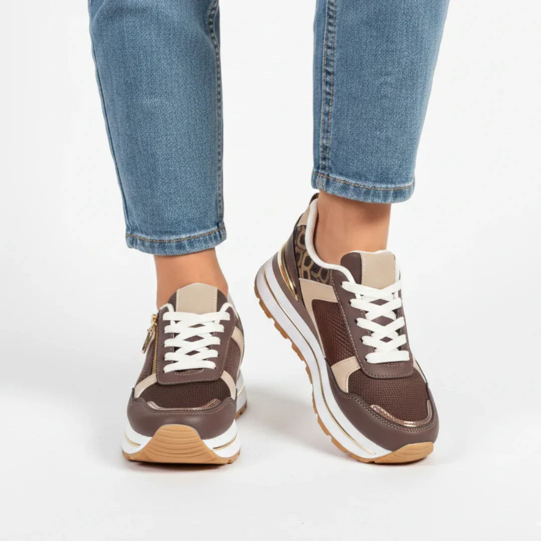 Brown women’s comfort sneakers with white laces, side zip detail, and cushioned sole