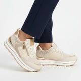 Beige women’s comfort sneakers with zip detail, white laces, and cushioned sole