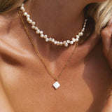 Gold pendant necklace with pearl strand and white clover charm