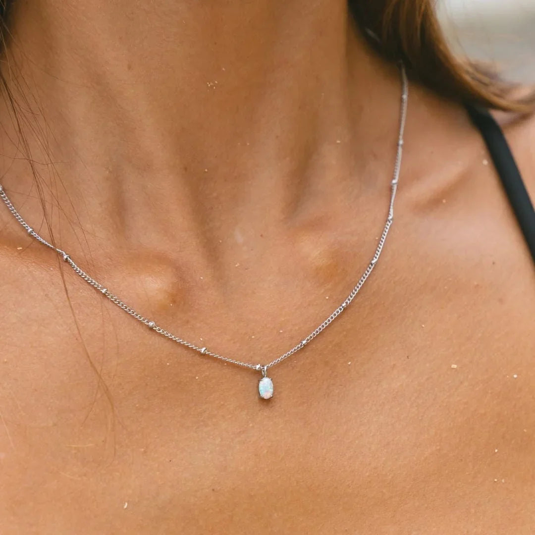 Silver opal pendant necklace with round opal charm centered on the neck